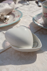 Romantic table setting. Heart shaped porcelain box with engagement ring in foreground.