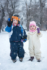 Little boy and girl waving while enjoying a snowy winter day.