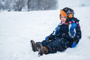 Little boy sitting in snow.
