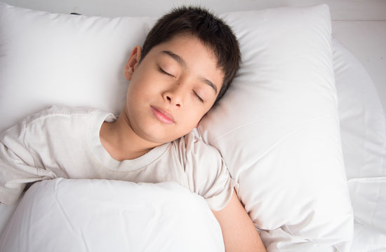 Little boy sleeping in the bed on  with white blanket cover