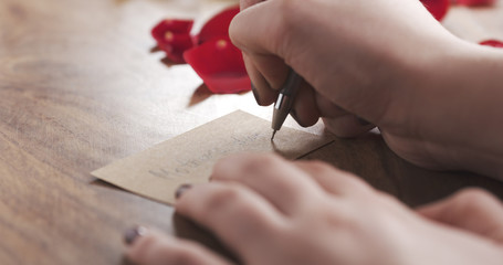 Obraz premium girl writes mothers day on a paper card on old wood background, 4k photo