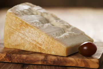 big chunk of italian parmesan cheese on wooden cutting board, simple rustic photo