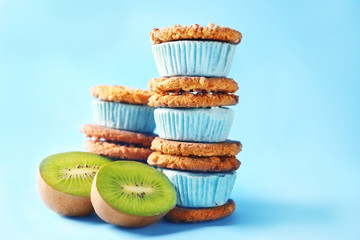 Delicious ice cream cookie sandwiches and kiwi on blue background