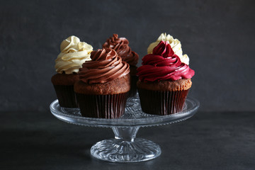 Glass stand with tasty chocolate cupcakes on dark background