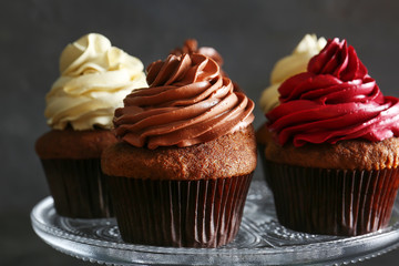 Glass stand with tasty chocolate cupcakes on dark background, close up
