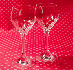 Crystal wine glasses with red romantic heart shapes inside, love