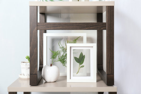 Frames with green leaves and ceramic apple on stand