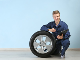 Young mechanic in uniform with a clipboard, on blue background