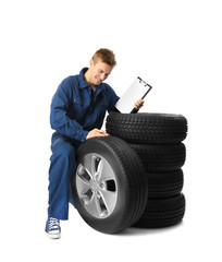Fototapeta premium Young mechanic in uniform with a clipboard on white background