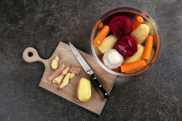 Bowl with  vegetables and cutting board on grey background