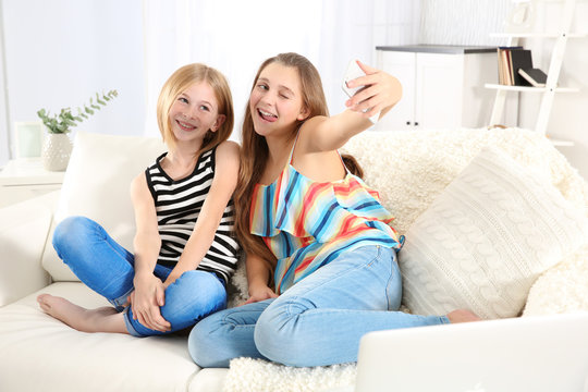 Two cute girls making selfie on sofa