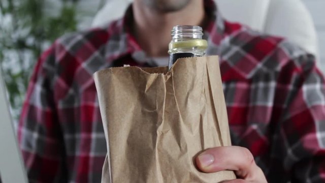 Man drinking bagged alchohol at office job