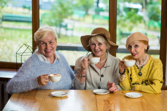 Women With Coffee Smiling. Three Happy Senior Ladies. Old Friends Meet In Cafe.