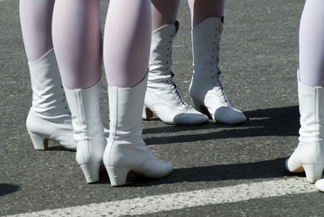 Attractive legs of young women in white boots standing on street