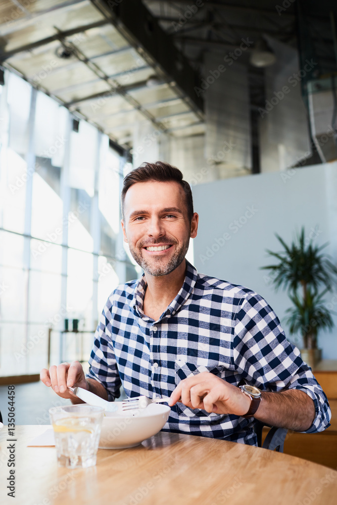 Wall mural Smiling man eating alone