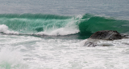 Emerald sea wave and rock
