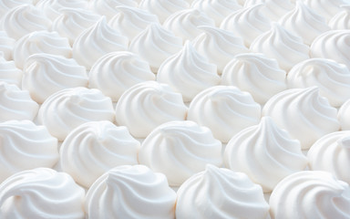 Closeup of white mini meringue swirls as food background.
