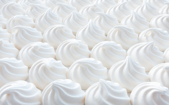 Closeup of white mini meringue swirls as food background.
