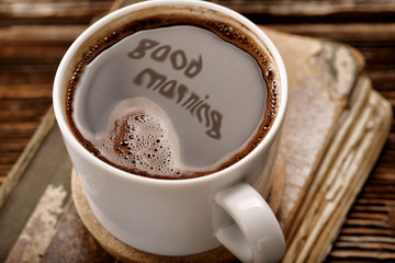 Cup of coffee and old book on wooden background