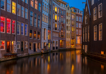 Fototapeta na wymiar Illuminated houses over canal with reflections at night, Amstardam, Netherlands, toned