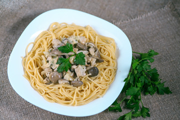 mushrooms of a veshanka and champignons in sauce with macaroni in a white plate on a table