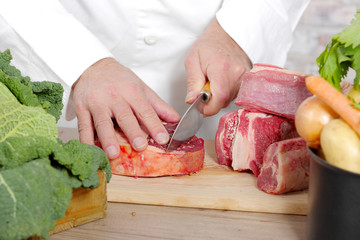 Chef cutting the meat on wooden board