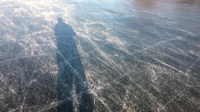 Shadow of a man Ice skating on a frozen lake near the river IJssel in The Netherlands during a beautiful winter day