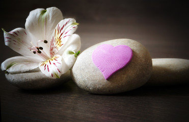 Three white stones with flower and heart on a wooden background, spa