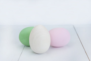 easter concept/three hand painted wooden eggs on a white wooden background
