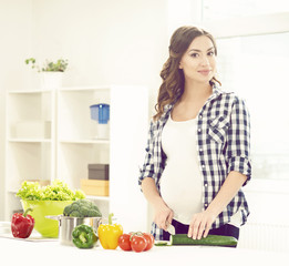 Beautiful pregnant woman cooking in the kitchen