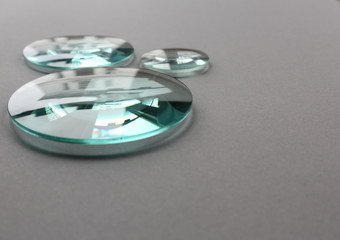 Optical glass lenses on grey background with reflections