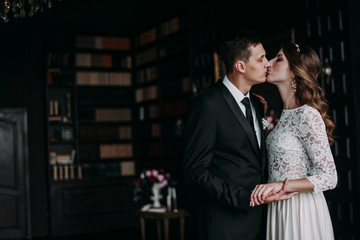 cute wedding couple in the interior of a classic studio decorated. hey kiss and hug each other