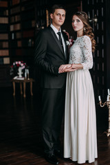 Fototapeta premium cute wedding couple in the interior of a classic studio decorated. hey kiss and hug each other