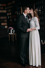 cute wedding couple in the interior of a classic studio decorated. hey kiss and hug each other