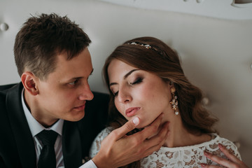 cute wedding couple in the interior of a classic white studio decorated. hey kiss and hug each other, holding hands looking at each other