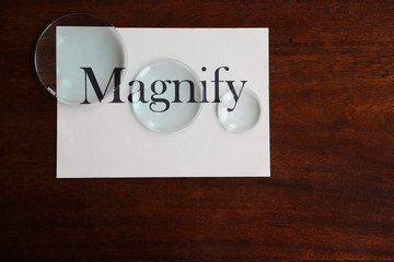 Magnify broad text on white sheet with glass lenses on antique desk 