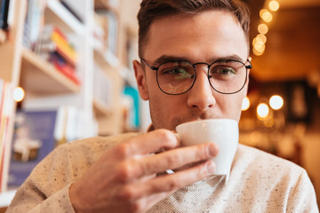 Handsome young man drinking coffee and look aside.