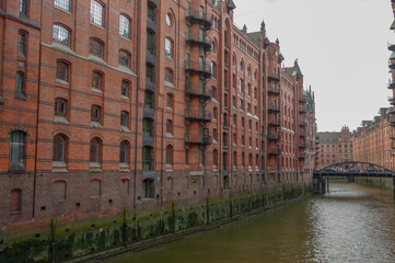 Fototapeta na wymiar HAMBURG, GERMANY - JULY 18, 2015: the canal of Historic Speicherstadt houses and bridges at evening with amaising skyview over warehouses, famous place Elbe river.