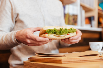 Cropped image of young man holding sandwich.