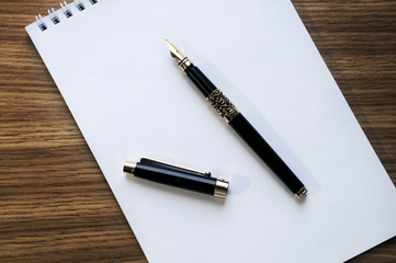 Notebook and fountain pen on wooden background