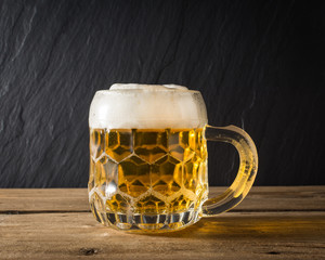 mug of beer on wooden table. front view