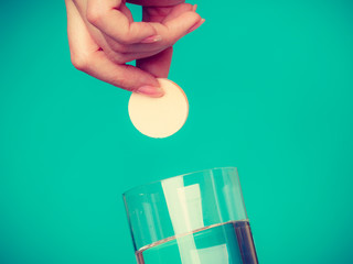 Person holding glass with water and effervescent tablet