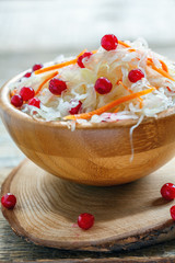 Sauerkraut with cranberries and carrot in a wooden bowl.