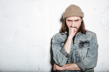 Handsome serious bearded hipster man over wall background.