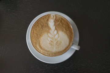 Cup of coffee on wooden table in cafe.