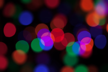 Abstract background with large coloured bohek lights on black.