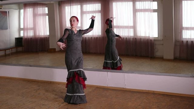 young woman dancing flamenco in front of mirror in studio