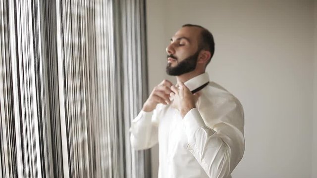 Groom buttons his shirt and puts on a tie