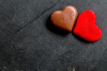 Chocolate hearts candies on black background Top view Copy space Valentines day postcard concept