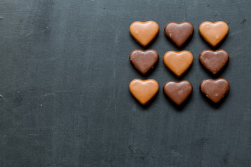 Chocolate hearts candies on black background Top view Copy space Valentines day postcard concept